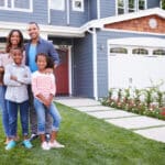 Happy family standing outside their home abroad, representing expats who may qualify for the foreign housing deduction.