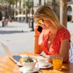 Woman working on a laptop in a café, reviewing finances that may be affected by the alternative minimum tax.