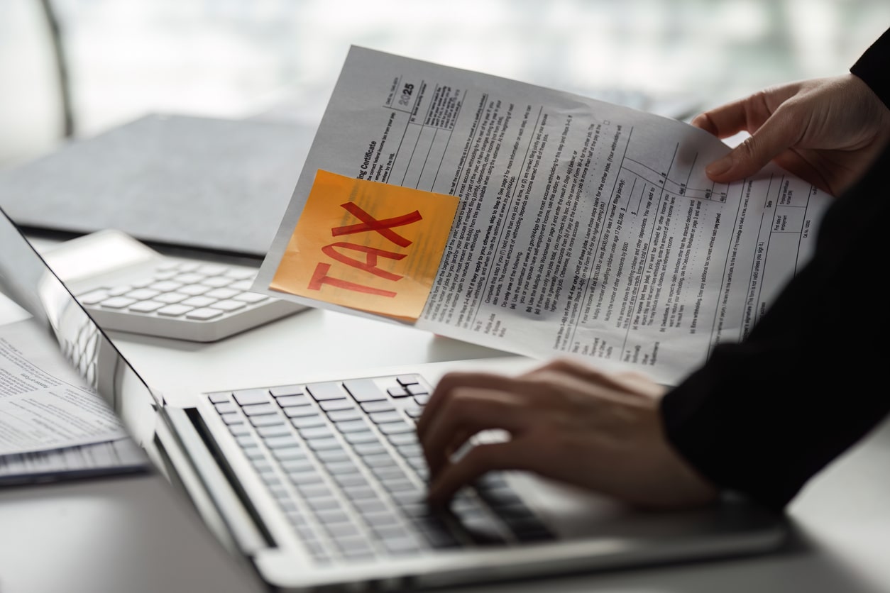 Individual working on tax paperwork and laptop, preparing to submit Form 4868 for a filing extension.