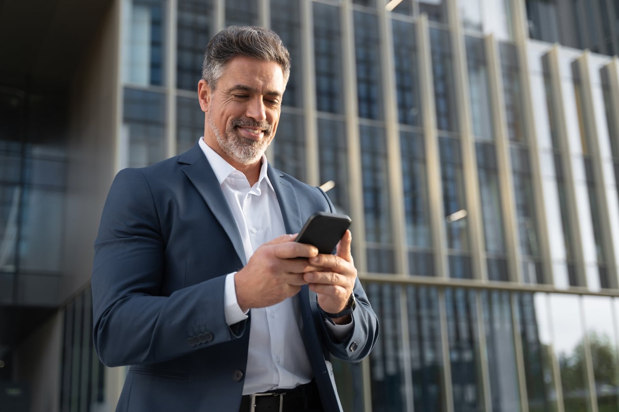 Confident businessman checks financial data on his phone, managing international income that may require Form 1118.