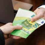Cash being handed across an office desk, symbolizing financial transactions that can raise broader questions around FBAR filing.