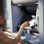 Young woman using an ATM, a reminder that foreign bank accounts like this may need to be reported under FBAR.