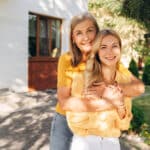 Senior mother and her adult daughter sharing a joyful hug, reflecting the family emotions that can surround selling inherited property.