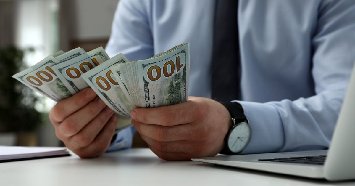 US expat counting hundred-dollar bills in preparation for sending large sums of money overseas.