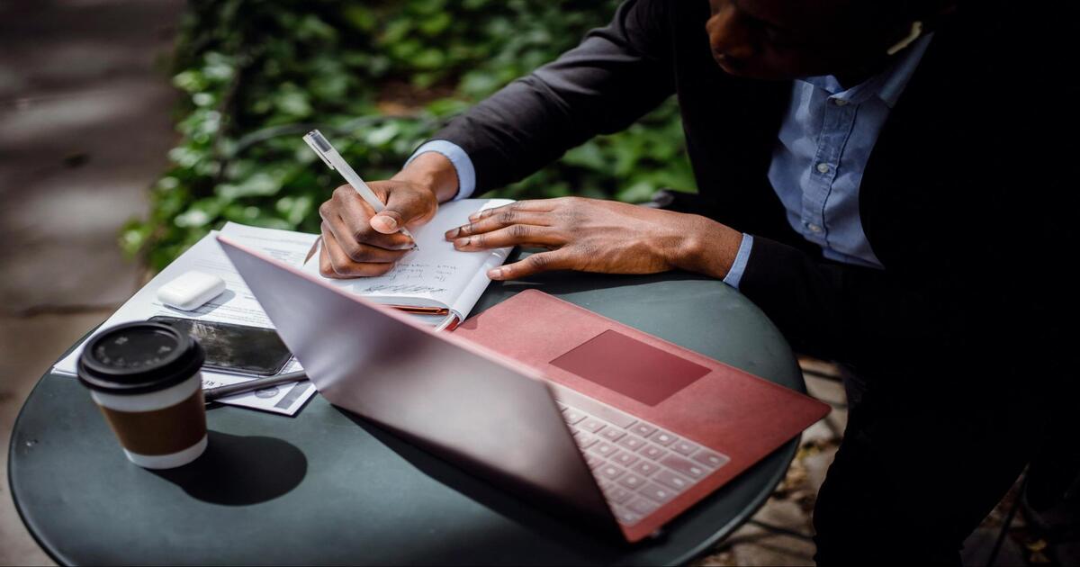 a man with a laptop writing down notes