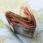Foreign currency spread across a world map, representing global income and the IRS streamline procedures for reporting missed foreign assets.
