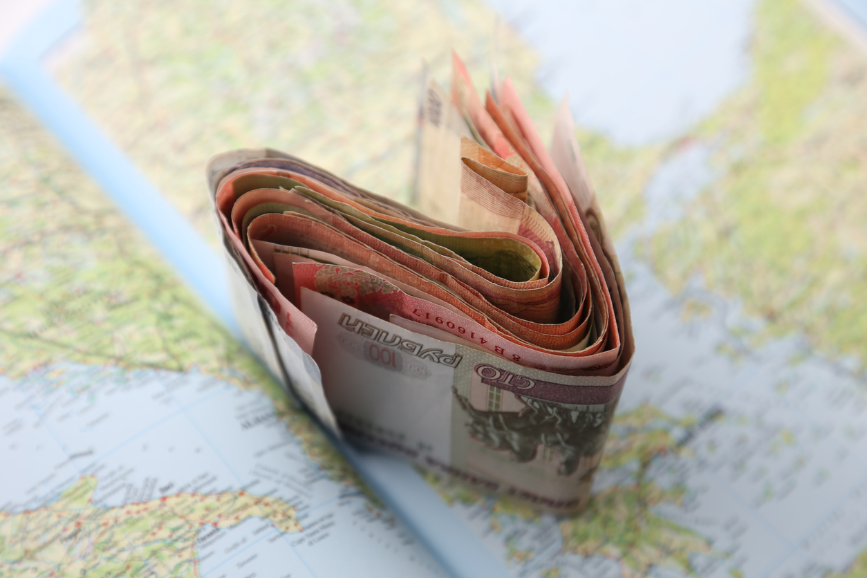 Foreign currency spread across a world map, representing global income and the IRS streamline procedures for reporting missed foreign assets.