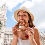 Young tourist holding a pretzel in Munich, capturing a familiar symbol of German culture.
