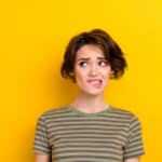 Unsure young woman biting her lip, capturing the feeling of realizing you may need to file Form 1040-X.
